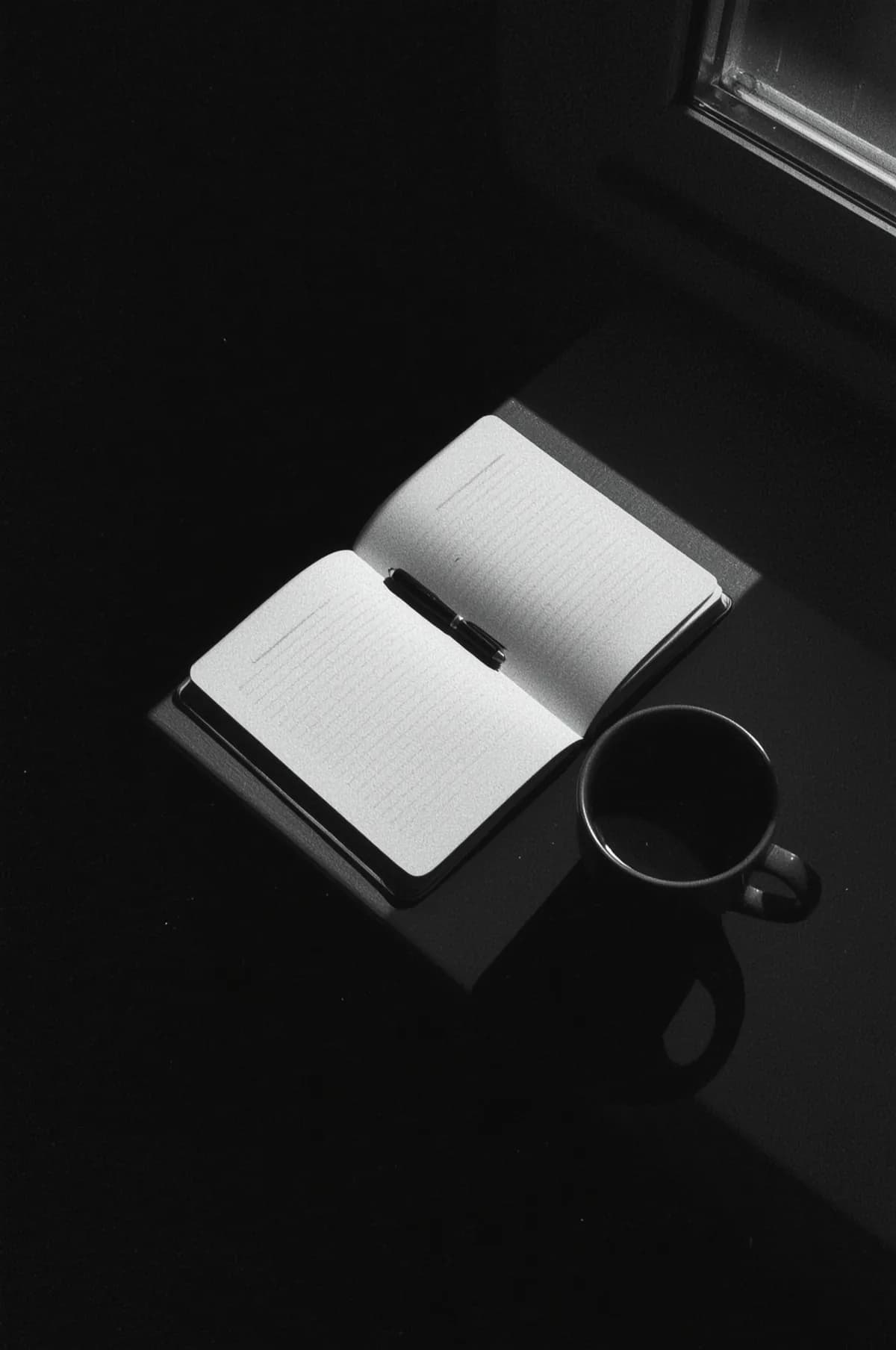An open notebook filled to its middle page, caught in hard window light