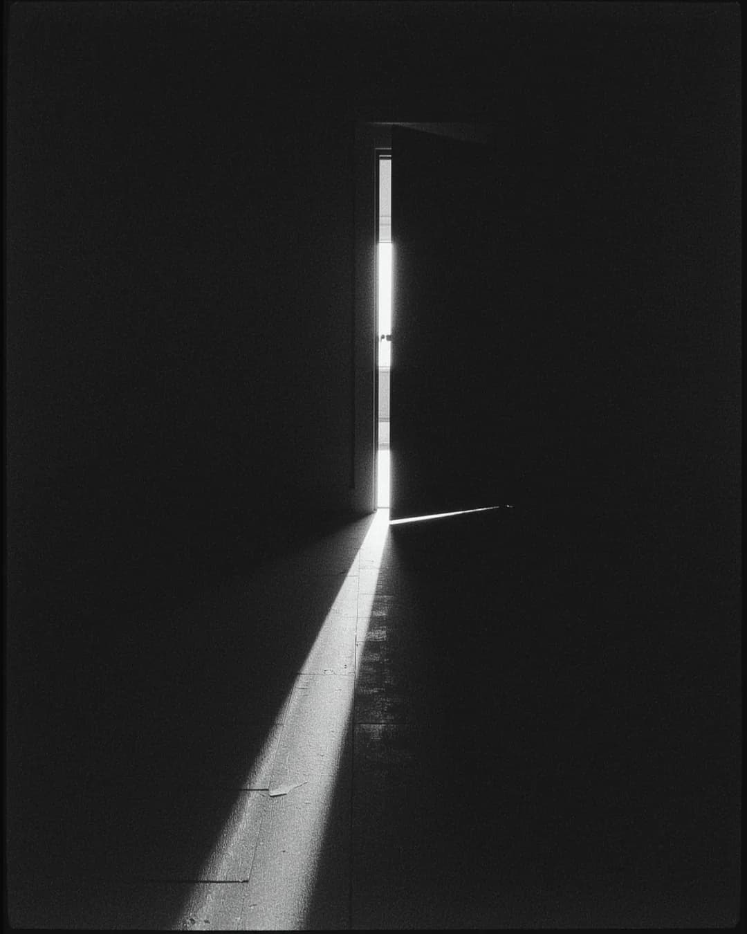Light entering through a partly open door in a dark hallway